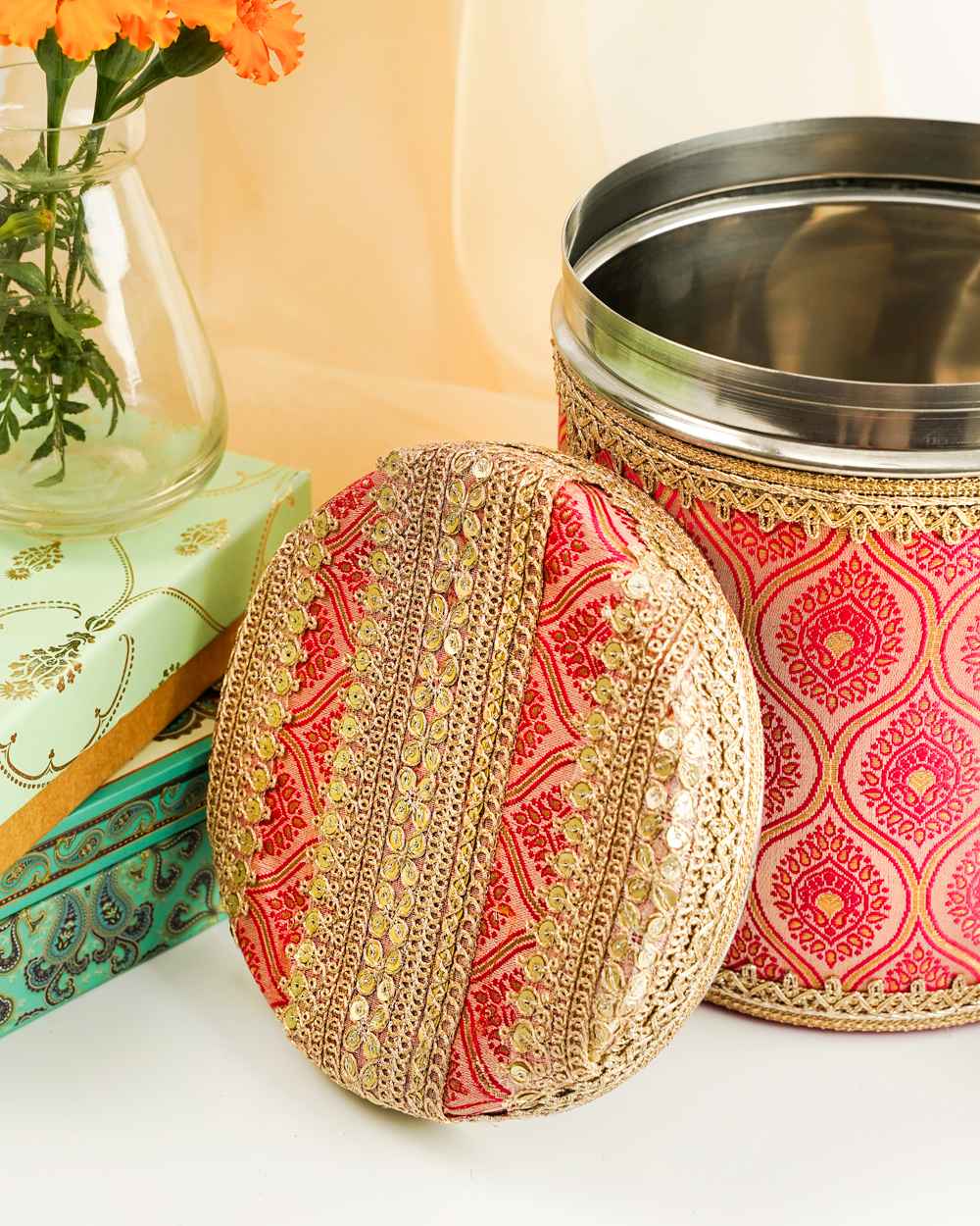 A close-up of the Gulaabi Ladoo/Bhaji Box by Navka Studio, showing its pink brocade and ornate gold sequin lid.