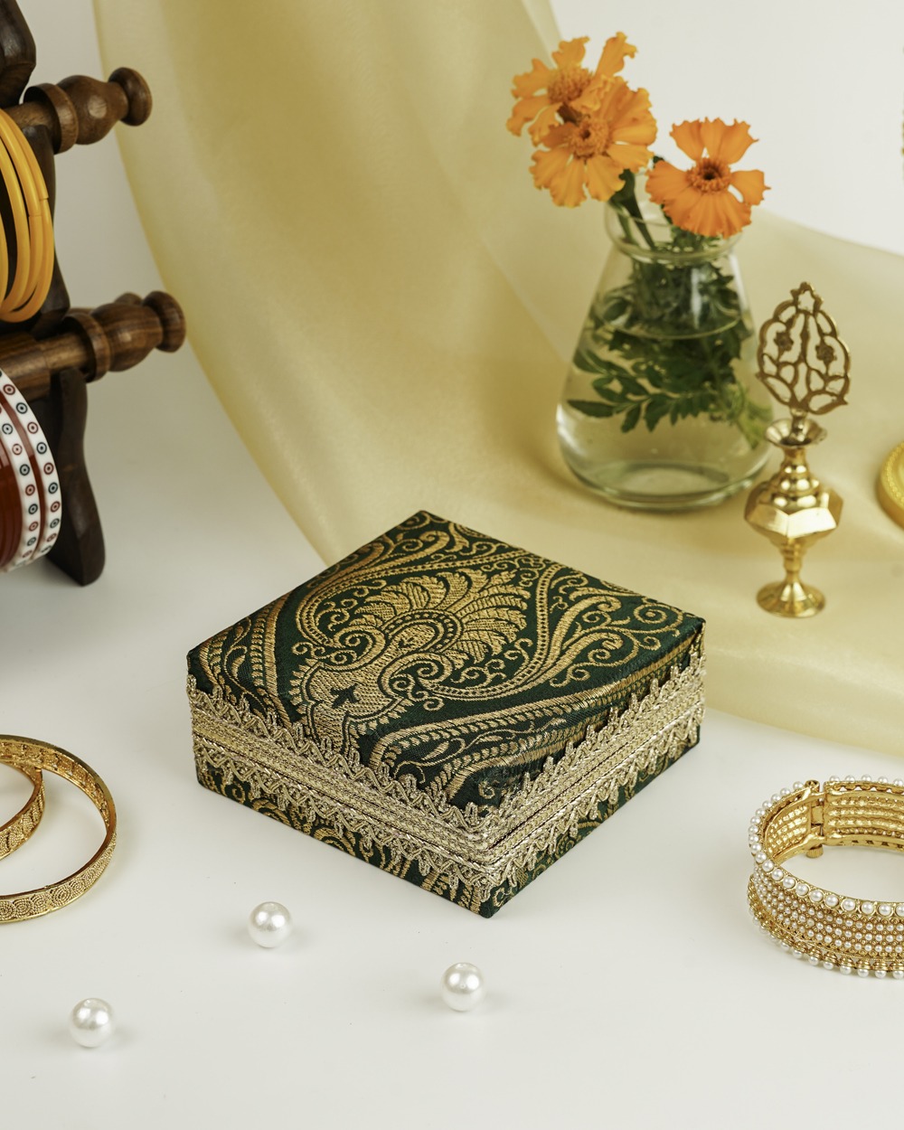 A square Baagh Brocade Kada Box by Navka Studio in green fabric with gold paisley brocade and delicate gold lace trim.