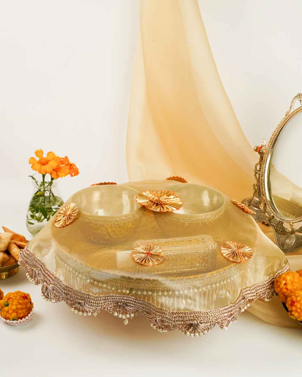 A Basant Haldi Thaal Set by Navka Studio, shown with its sheer gold organza cover adorned with gota flowers and pearl trim.
