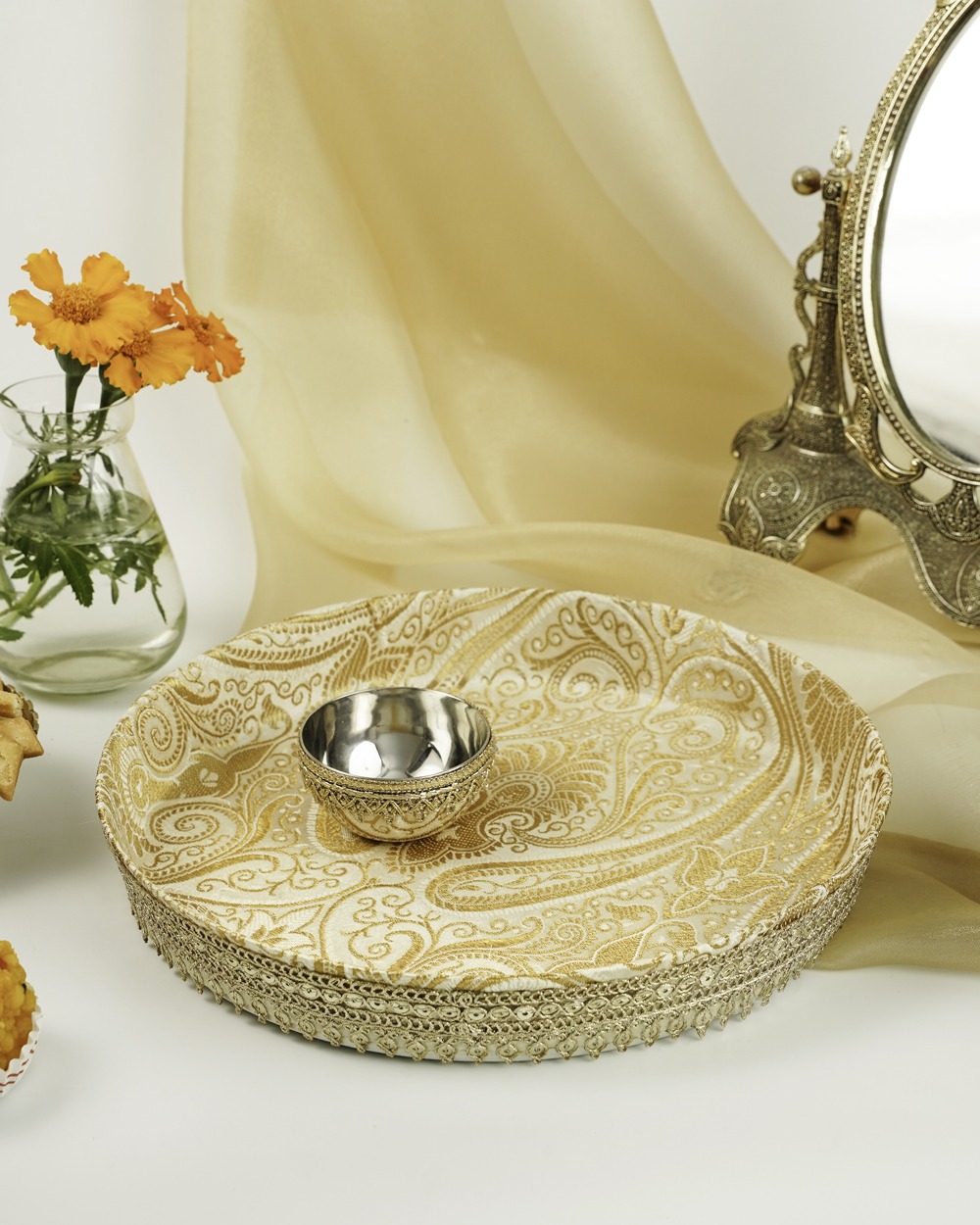The elegant Noori Tikka Thaal from Navka Studio, styled with a matching decorative bowl, highlighting its gold paisley fabric and detailed border.