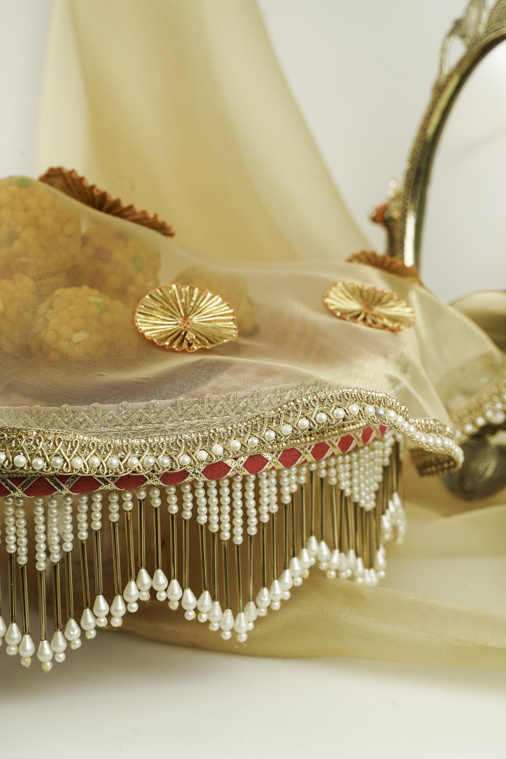 The Bahaar Shagun Thaal with Cover by Navka Studio, shown without the cover to display its round pink and gold floral brocade base and elegant pearl fringe, arranged in a festive setting.