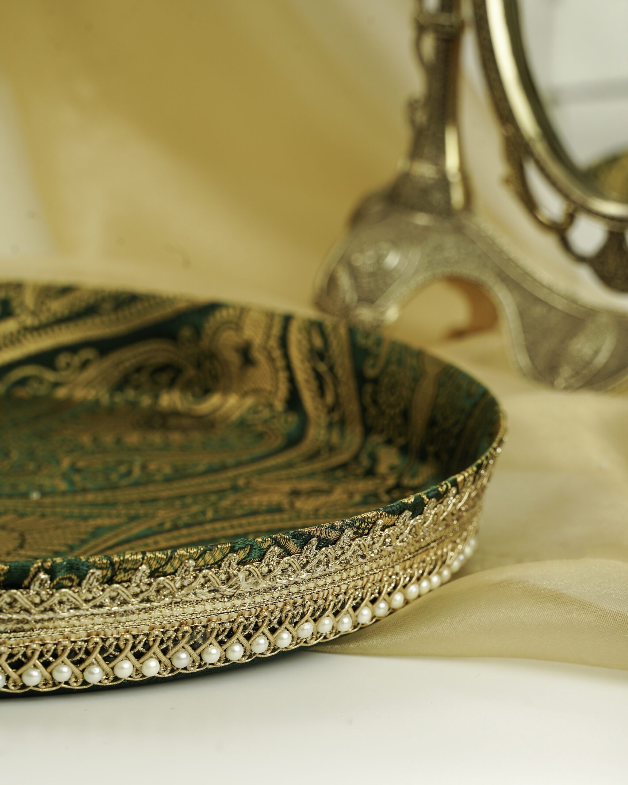 Beautiful Baagh Shagun Thaal with Cover A close-up of the Baagh Shagun Thaal with Cover by Navka Studio, detailing its rich green paisley brocade, gold lace, and pearl trim.