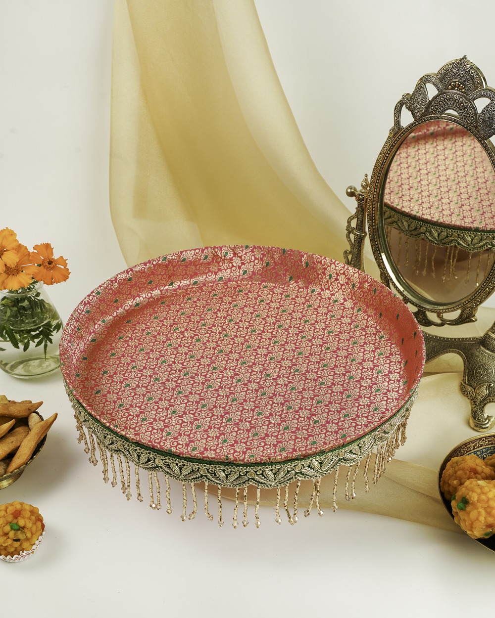 Gulzar Shagun Thaal with Cover by Navka Studio – an elegant handcrafted thaal in pink and gold hues with intricate detailing, displayed with festive sweets and decorative accents.