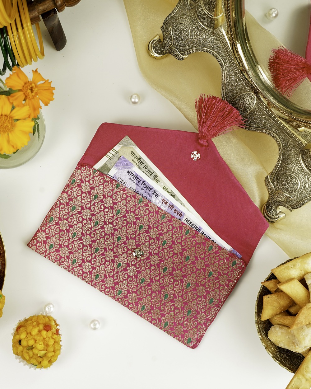 The Gulzar Brocade Shagun Envelope by Navka Studio, displayed open with a cash note inside, showcasing its beautiful brocade pattern and solid pink silk interior.