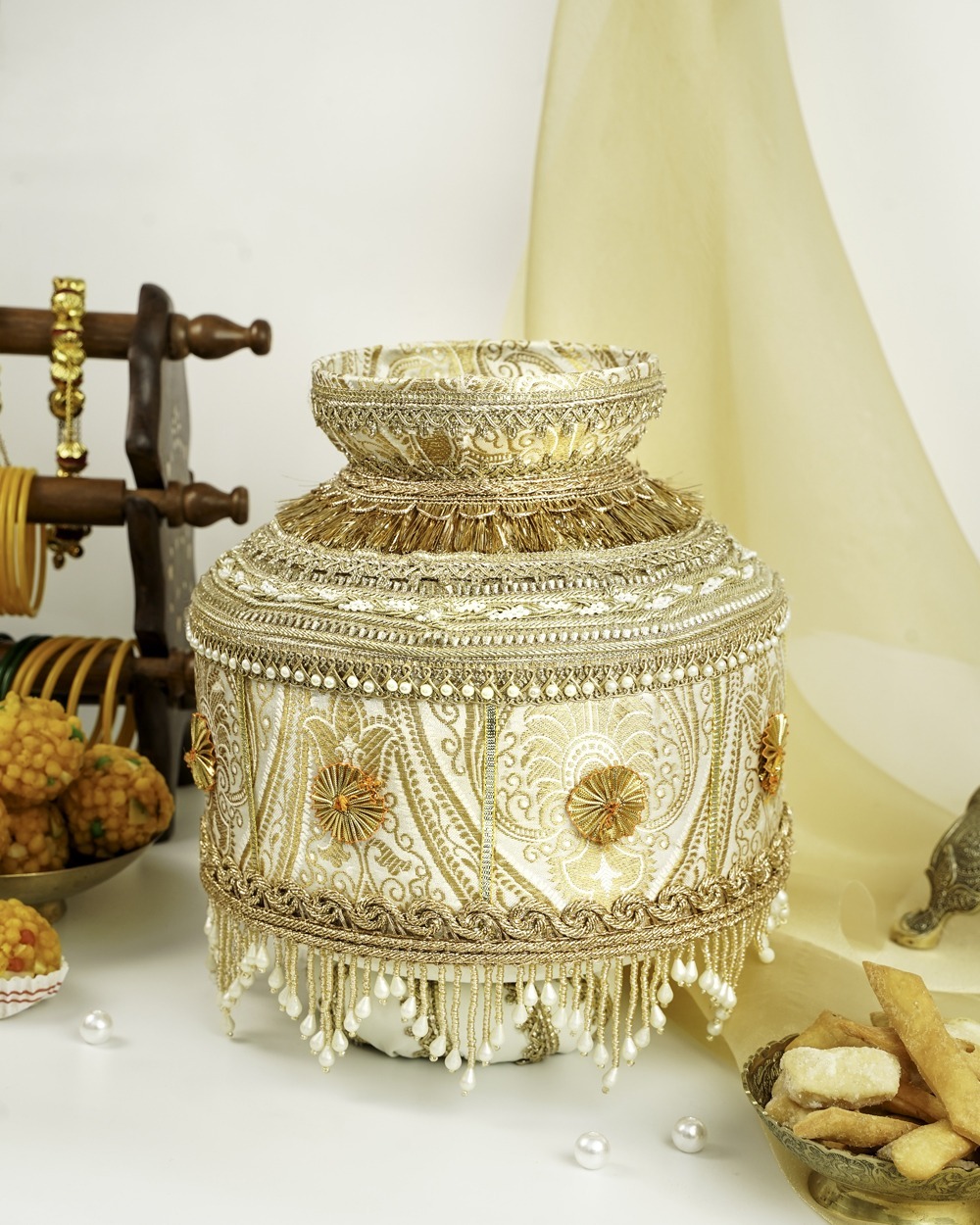 An ornate Noori Brocade Jaggo by Navka Studio, in cream and gold brocade, adorned with gota flowers, lace, and pearl tassels.