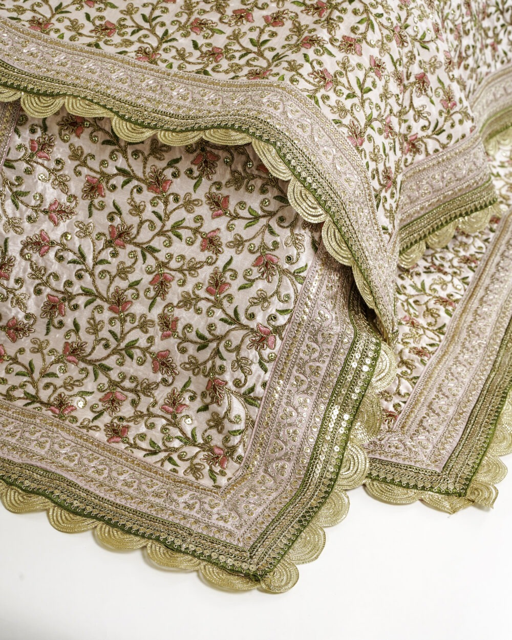A close-up of the Bahaar Rumala Sahib, showing its detailed pink and green floral embroidery on a light background with gold scalloped border.
