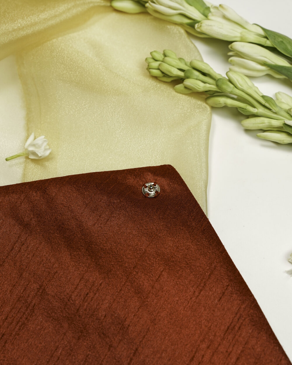 Elegant Saaj Silk, Full Gota work with Gold trims, Trousseau Bag, Red fabric envelope pouch with gold striped flap and fringe detailing, held by hands on a decorative surface with flowers.