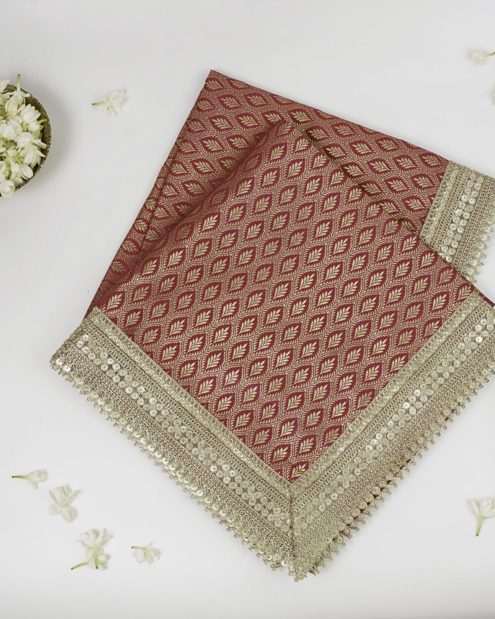 Close-up view of red and gold Sifat Rumala Sahib showing detailed golden embroidery and border design with shimmering fabric texture.