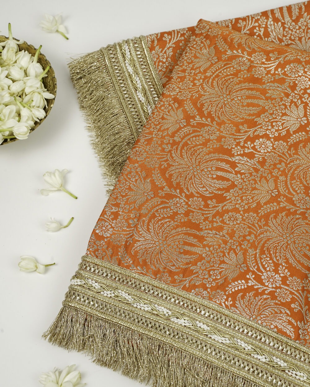 Suneheri Rumala Sahib,Orange and gold brocade fabric with intricate floral pattern and golden fringe border.