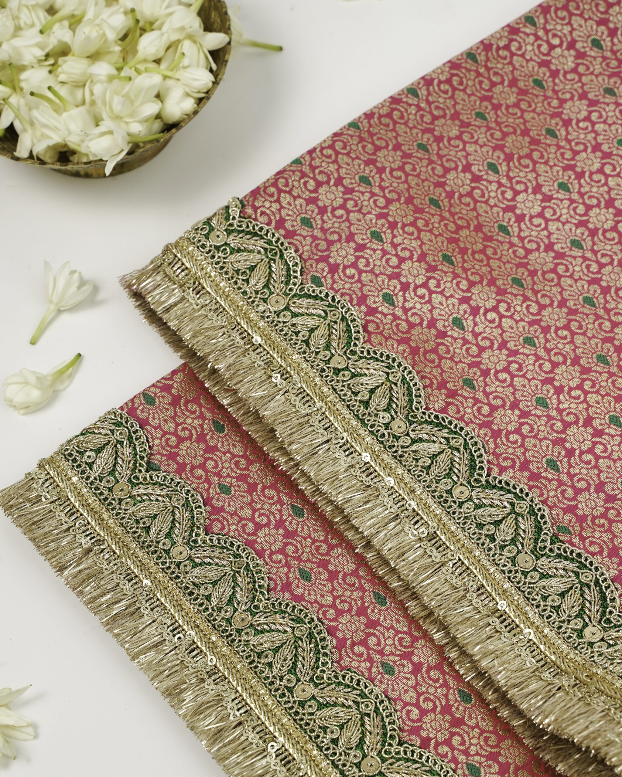Gulzaar Rumala Sahib | Floral Pooja Cloth | Navka Studio A close-up of the Gulzaar Rumala Sahib by Navka Studio, showing the vibrant pink and gold brocade with its intricate green and gold embroidered border.