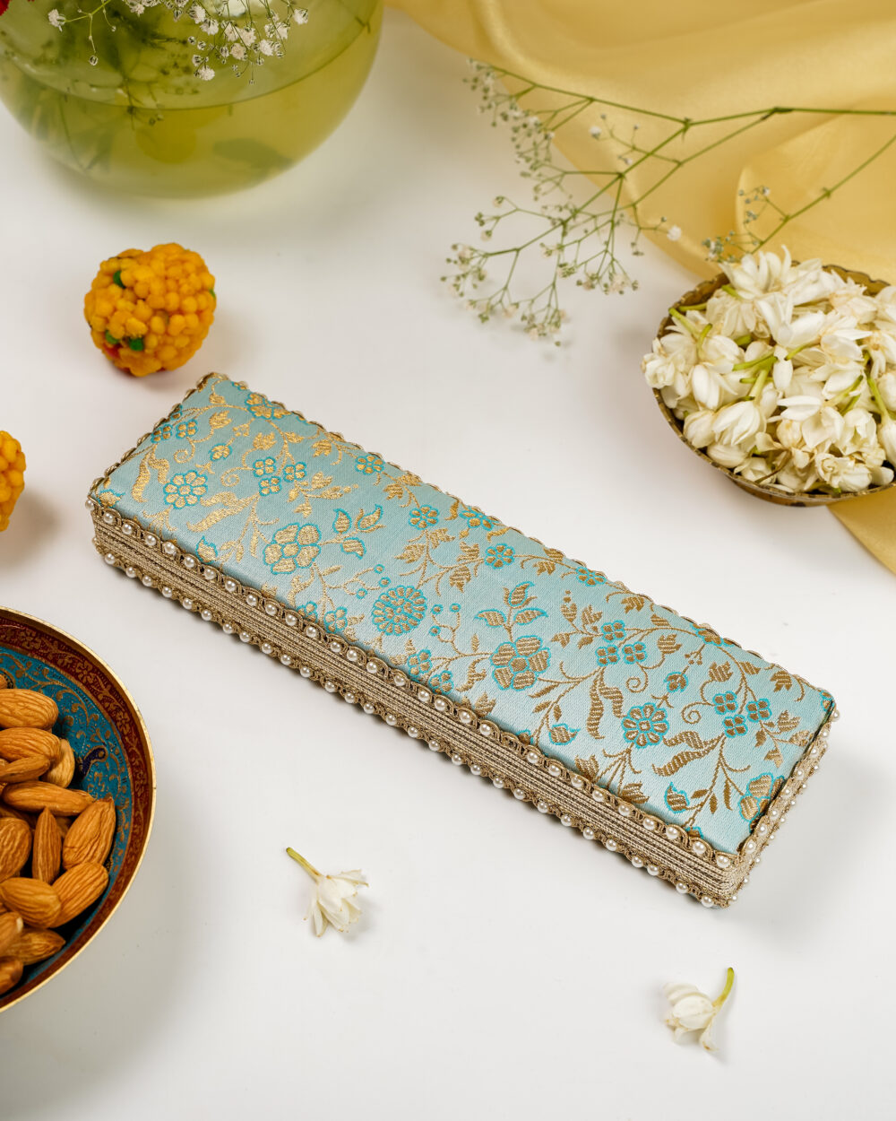 The Navka Seher Brocade Chain Box in light blue and gold, designed for safely storing necklaces and chains.
