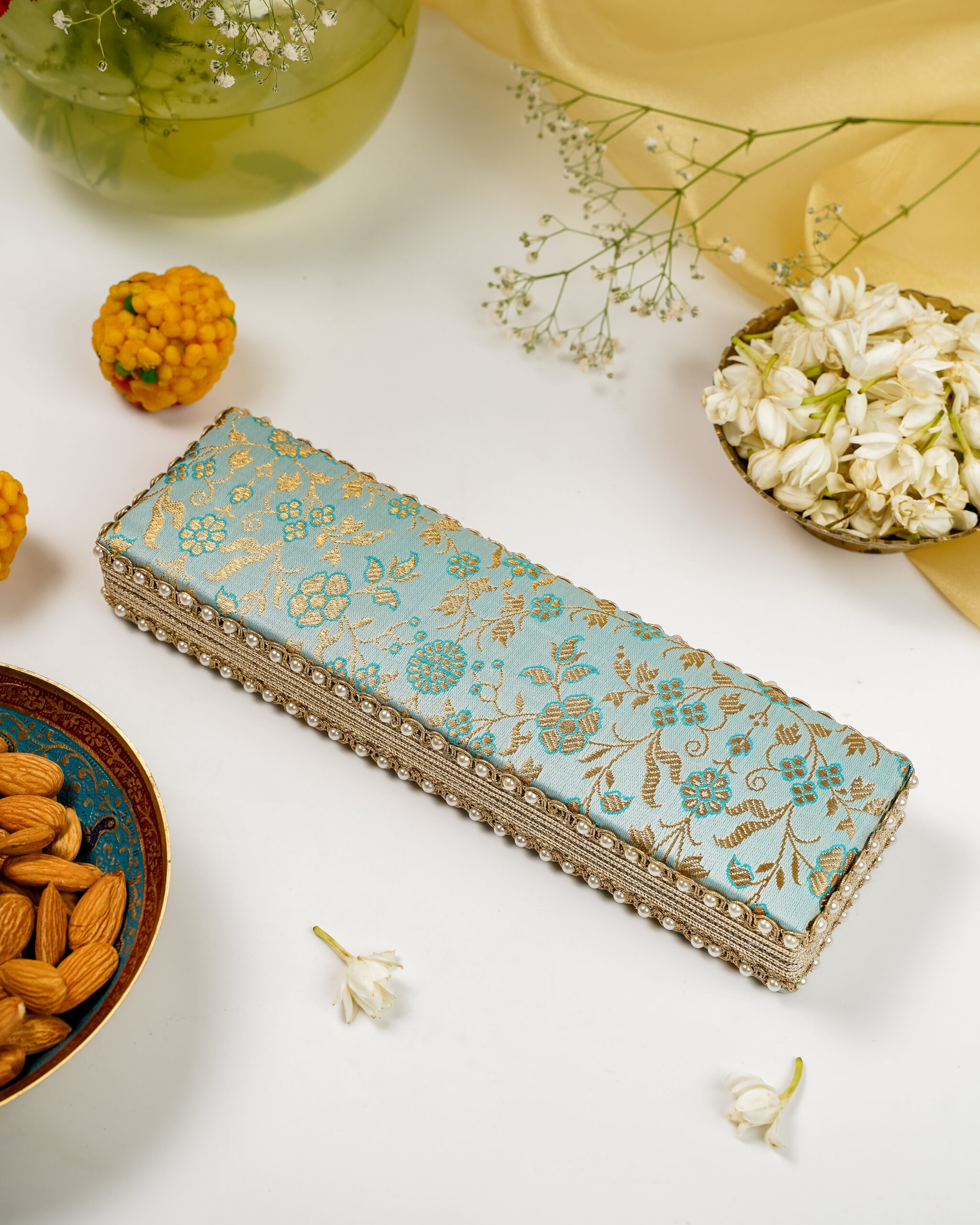 The Navka Seher Brocade Chain Box in light blue and gold, designed for safely storing necklaces and chains.